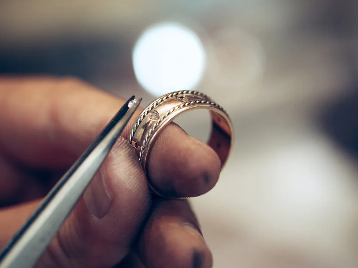 Jeweler setting diamond on gold ring.