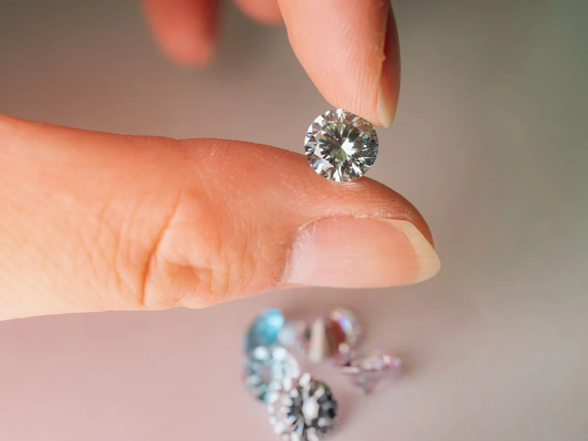 Hand holding round brilliant cut diamond gem.