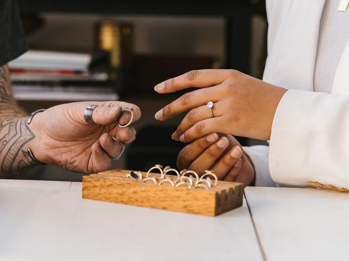 Customer trying rings with jeweler assistance.