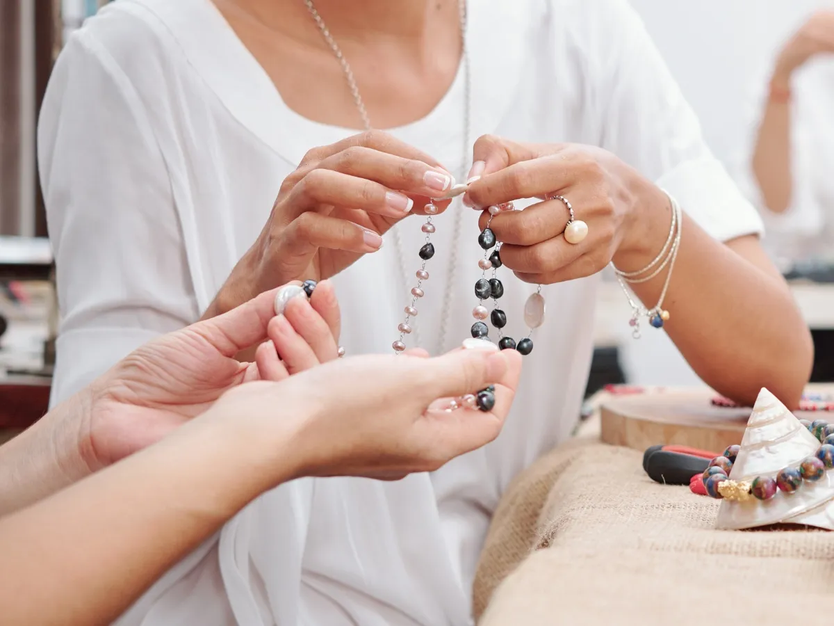 Two people examining pearl bead necklace.