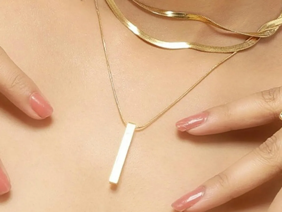 Close-up gold bar pendant necklace on skin.