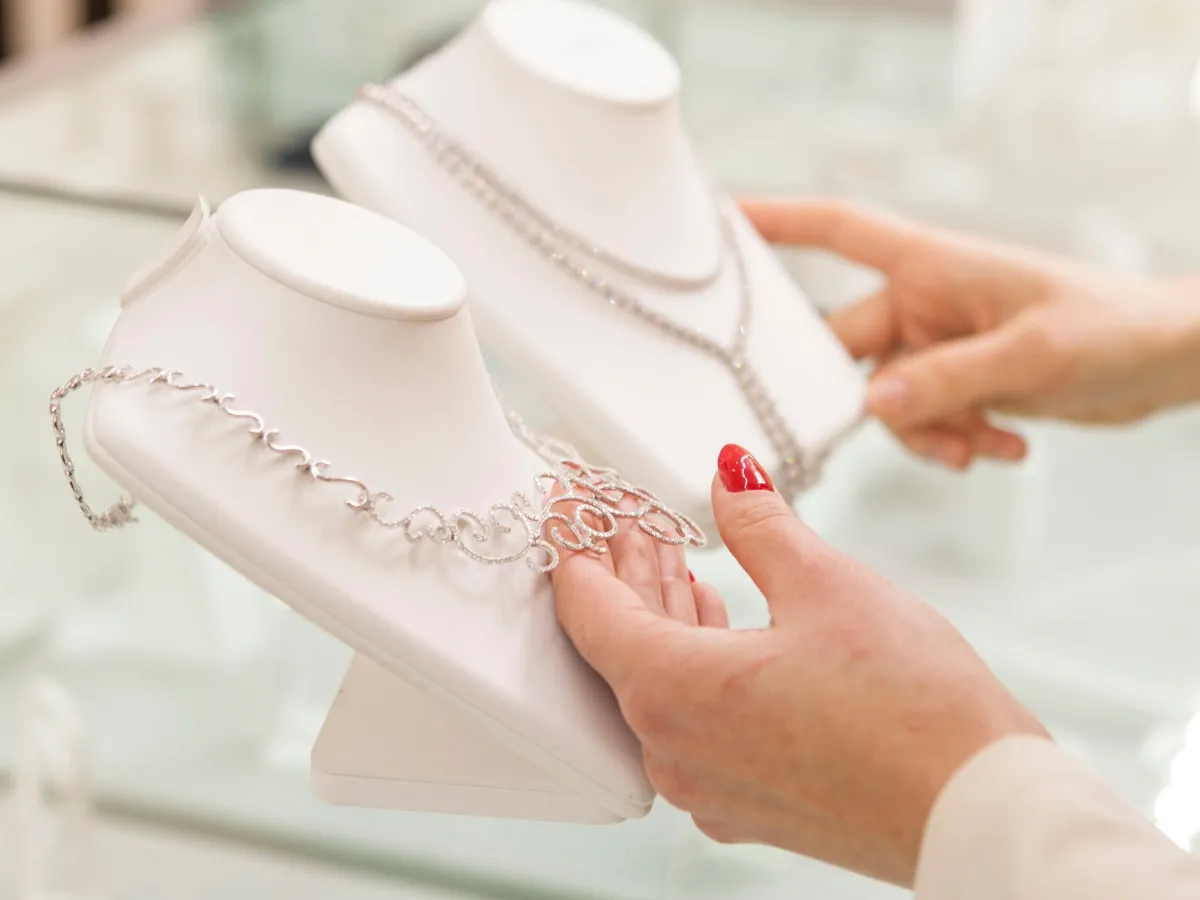 Woman selecting diamond necklace from display.