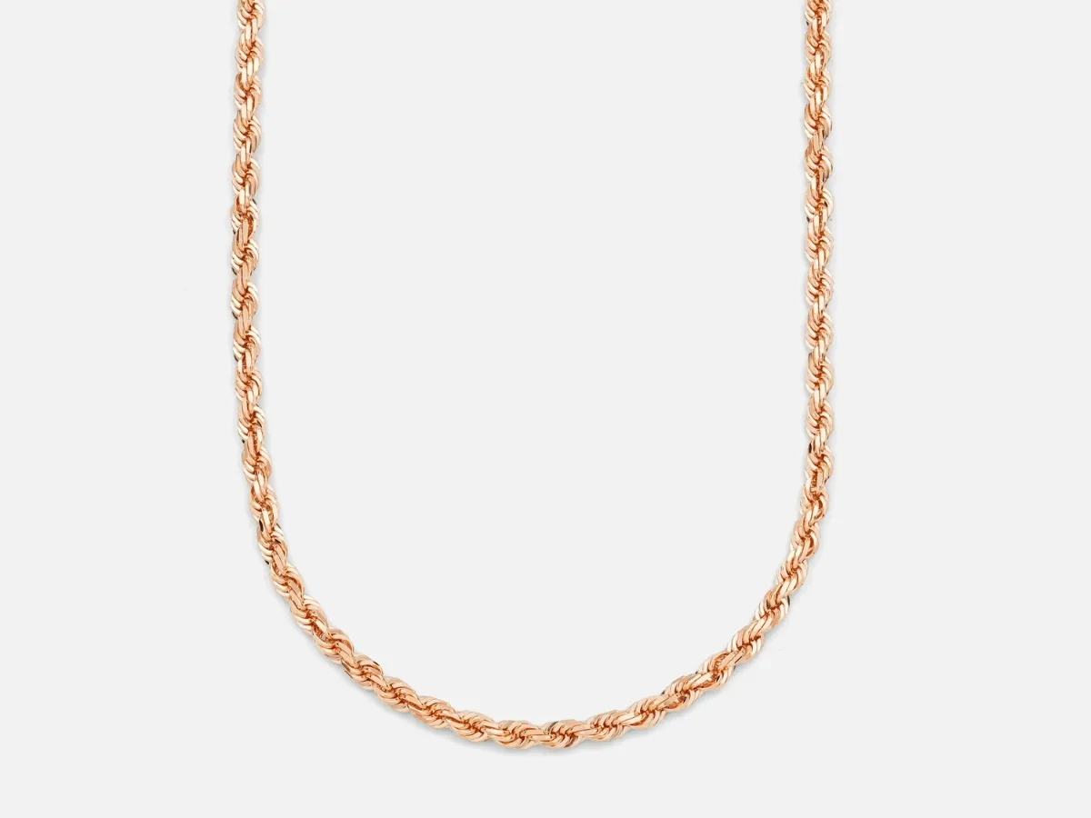 Rose gold rope chain necklace on white background.