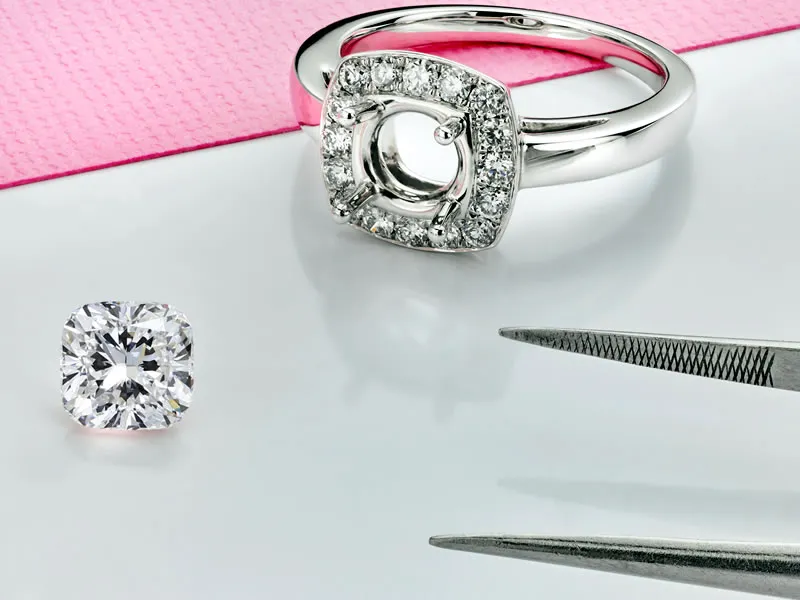 A pair of tweezers getting ready to pick up a loose cushio shaped diamond to place into a ring semi-mount at Van Adams Jewelers 