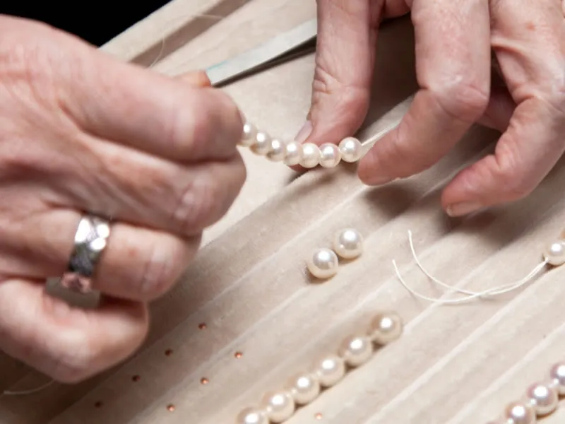 A jeweler restringing a pearl necklace at Van Adams Jewelers Snellville, GA