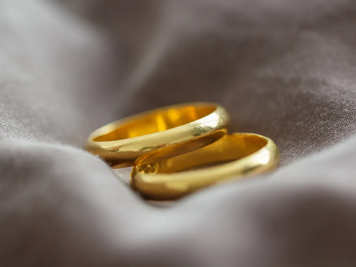 Two gold wedding bands on fabric.