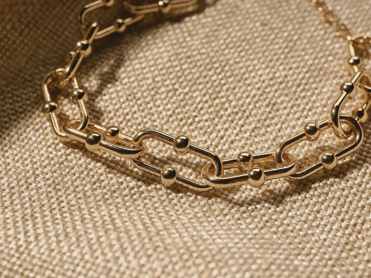 Chunky gold chain bracelet on fabric.