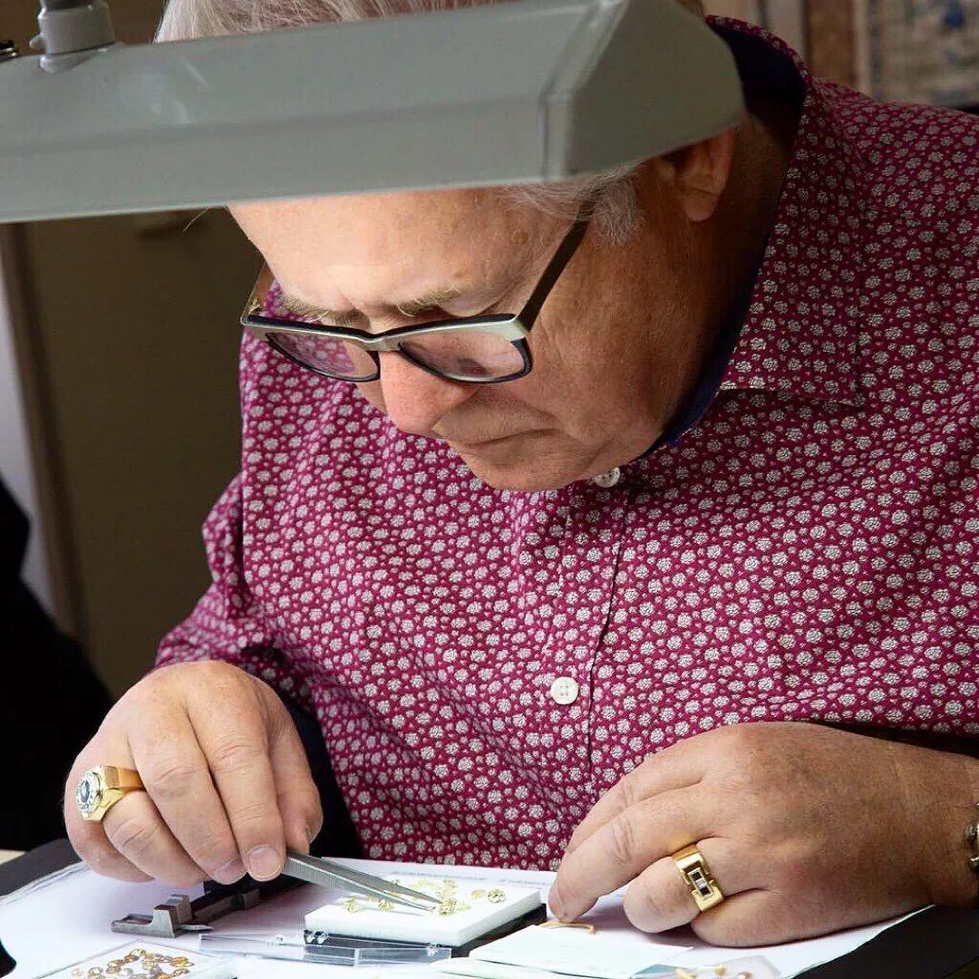 Jeweller examining fine jewellery under a lamp, showcasing craftsmanship at Vandenbergs Fine Jewellery in Winnipeg.