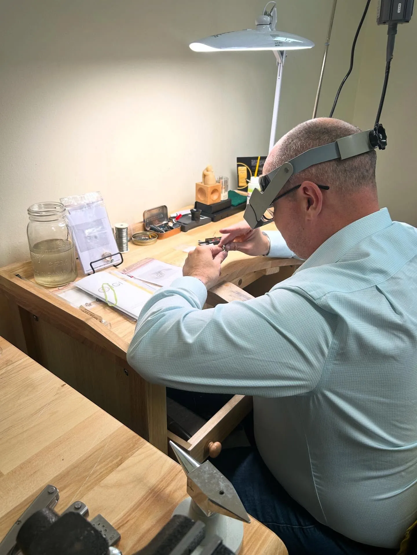A jeweller using a magnifying visor to work on a piece at Vandenbergs Fine Jewellery in Winnipeg.