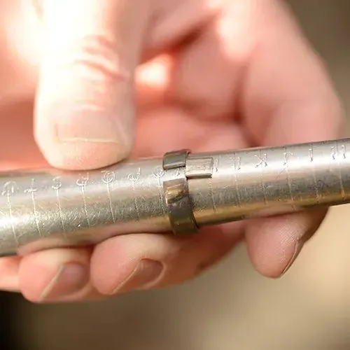 A hand holding a metal ring sizer tool, used for measuring ring sizes at Vandenbergs Fine Jewellery in Winnipeg.