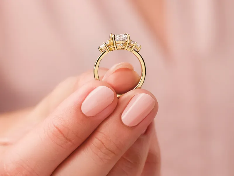 Woman holding a three stone engagement ring out