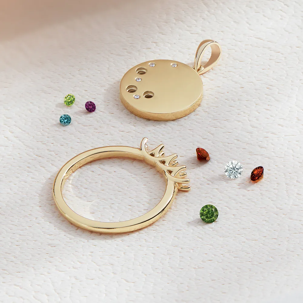 Stoneless ring laying flat with multiple colored stones and a loose pendant scattered next to it