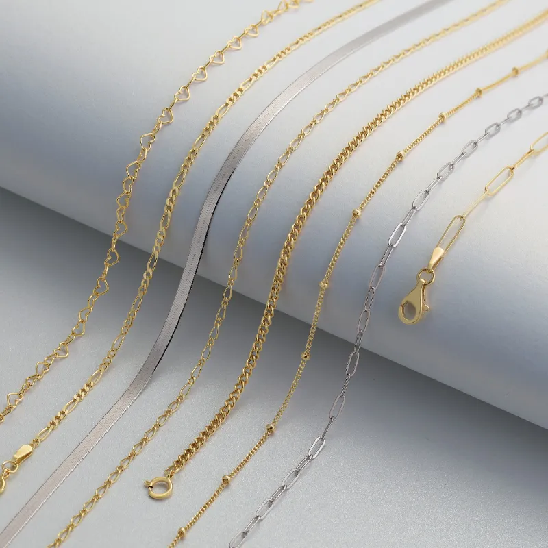 Various gold and silver chain styles laying on white surface