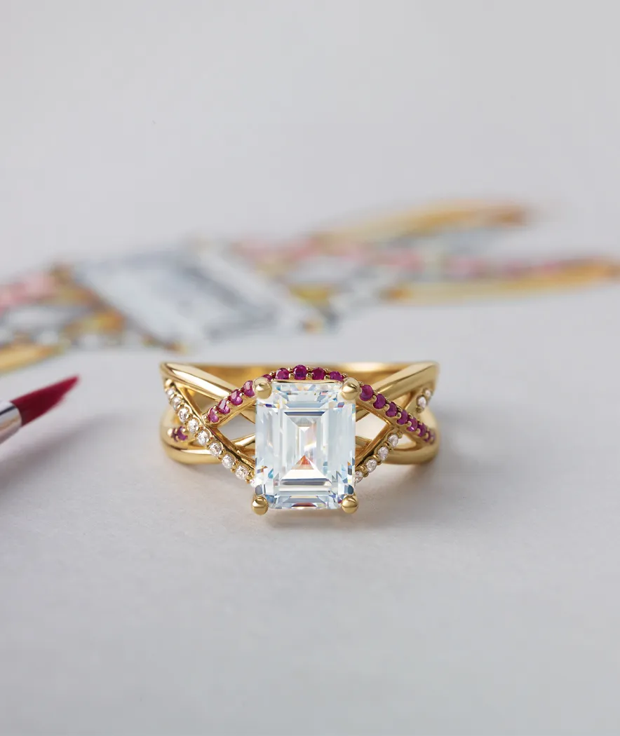 Completed diamond ring with small red stones laying on top of sketch of the same jewelry piece