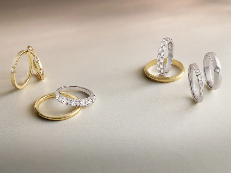 Several gold and silver diamond wedding bands on beige surface