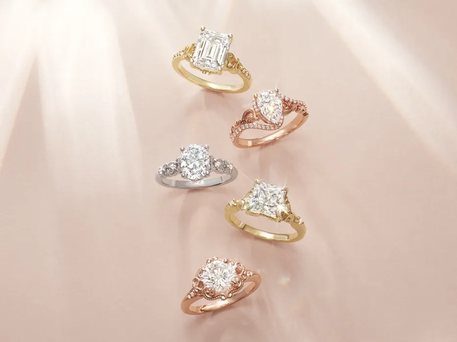 Various engagement ring styles in gold, silver, and rose gold metals on light pink background