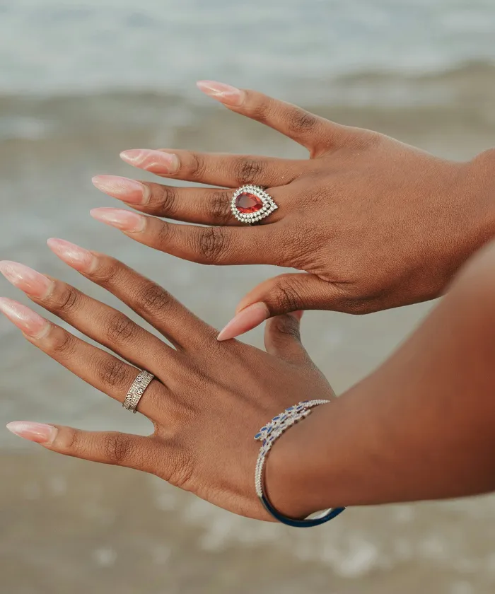 Woman with long nails wearing rings and a bracelet by the beach