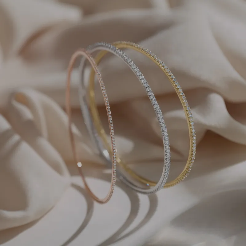 Three bracelets with different metals on beige sheet background