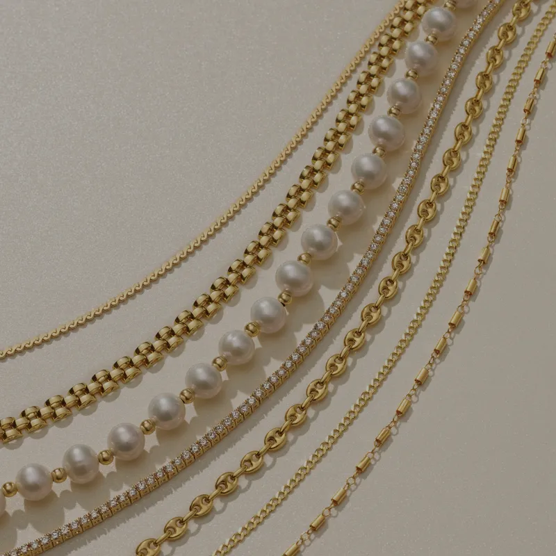 Various gold and pearl chains laying out on tan background