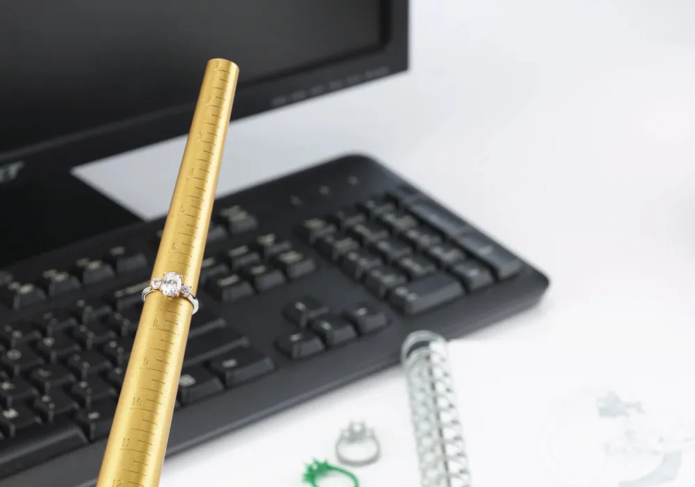 Engagement ring on ring resizer in from of a computer