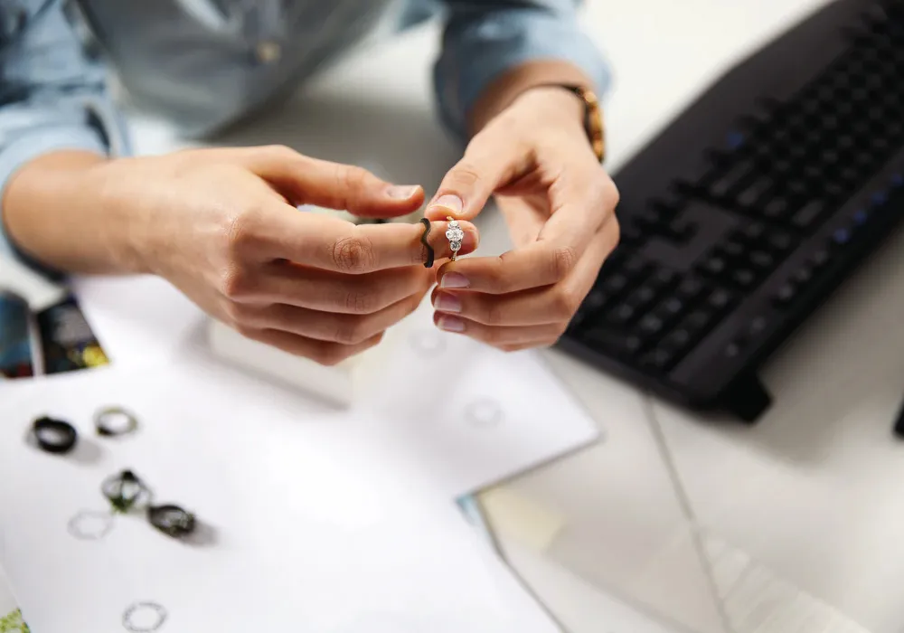 Person holding a diamond engagement ring on index finger with wedding band wax mold