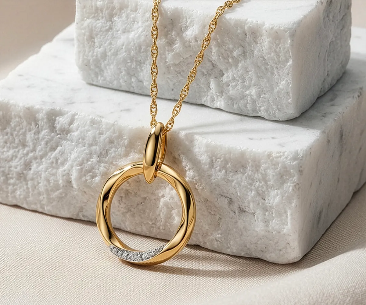 Gold pendant necklace with diamond accents on a marble background.