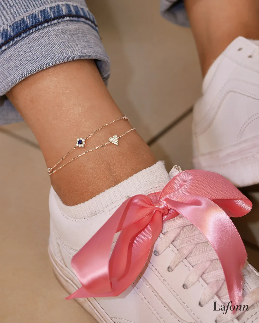 Anklet with small charms on a foot in water, showcasing jewelry.
