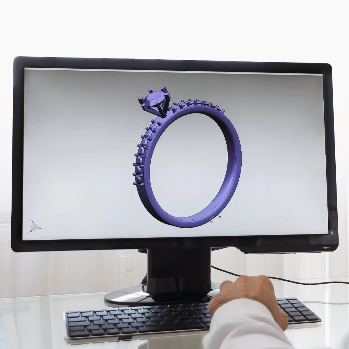 A person designs a purple ring using 3D software on a computer screen.