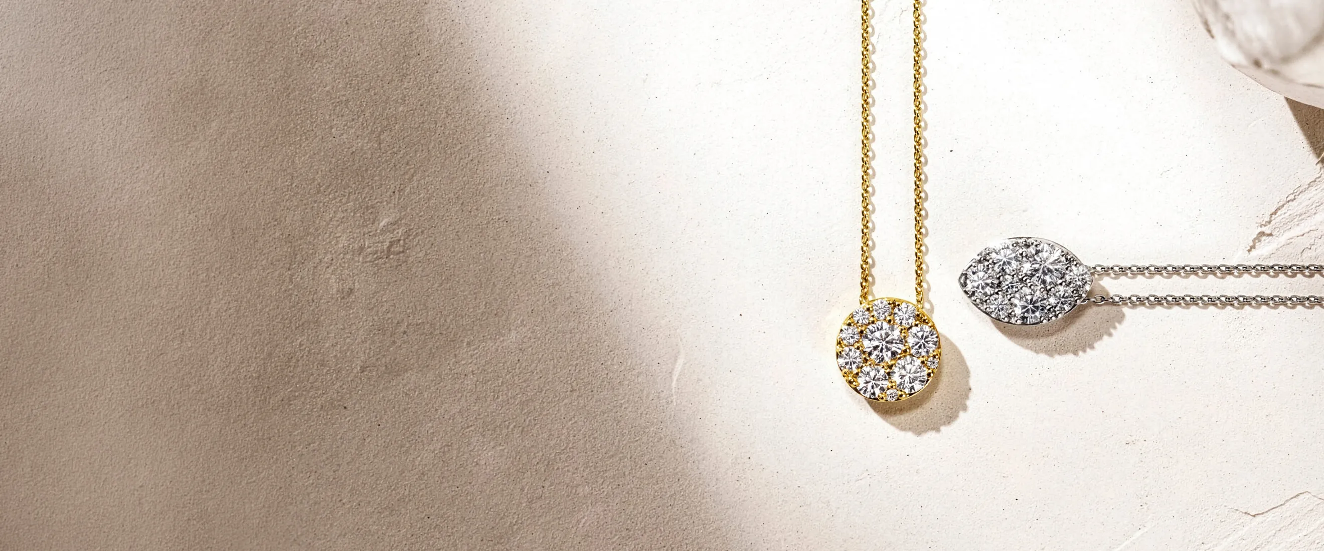 Gold and silver diamond necklaces on textured surface.