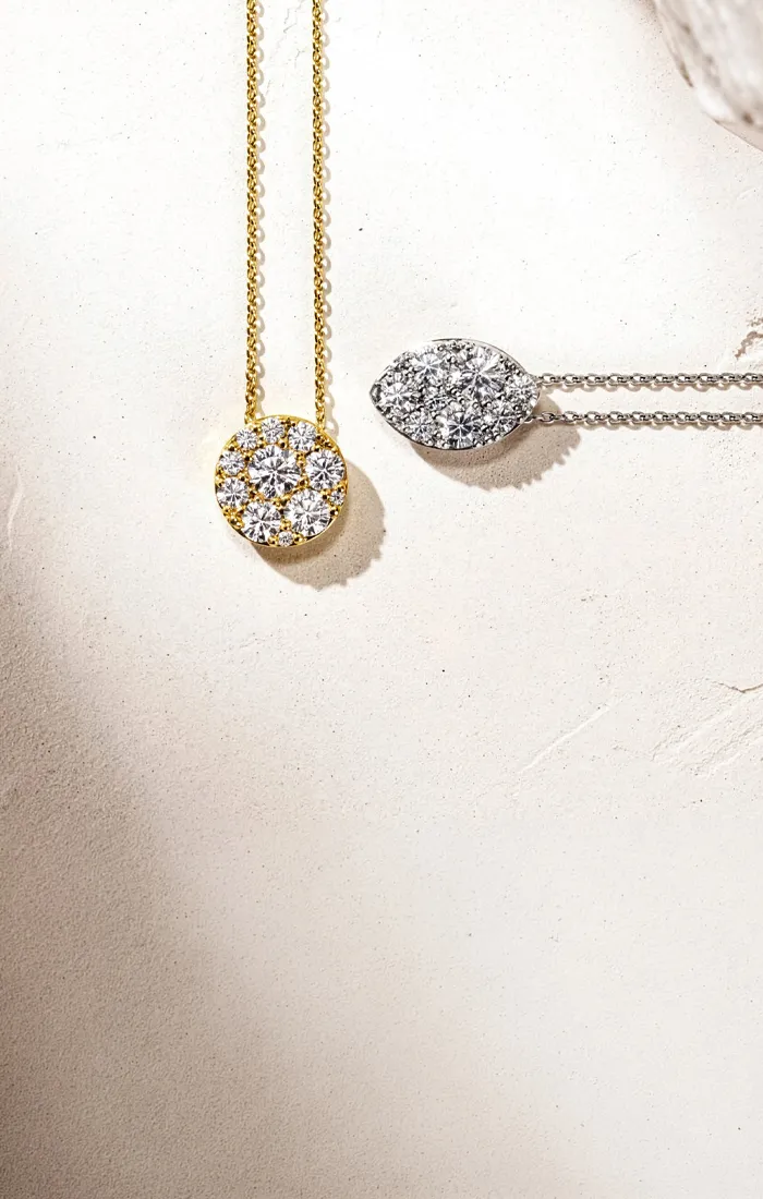 Gold and silver diamond necklaces on textured surface.