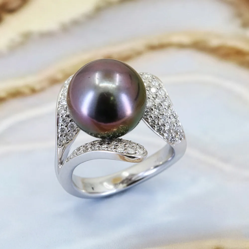 Silver ring with a large black pearl and diamond accents on a light background.
