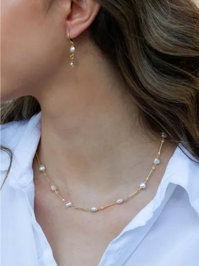 Woman wearing pearl and gold necklace and earrings, showcasing jewelry. Explore Mother's Day gifts under $1,500.