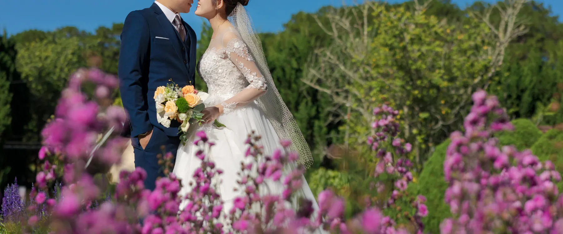 Bride and groom sharing a tender moment, foreheads touching, with the bride holding a floral bouquet. Shop engagement now!