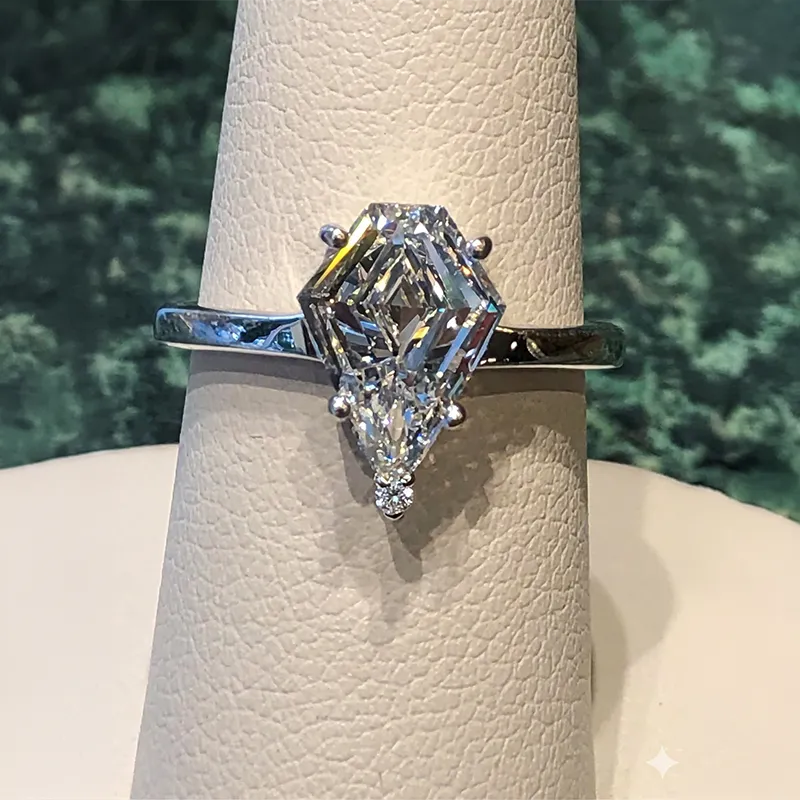 A hand with a large emerald-cut diamond ring on the ring finger.
