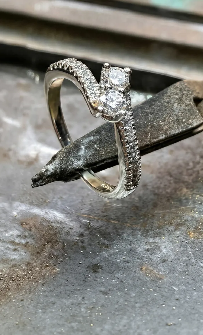 A diamond ring held by pliers on a workbench, showcasing craftsmanship.