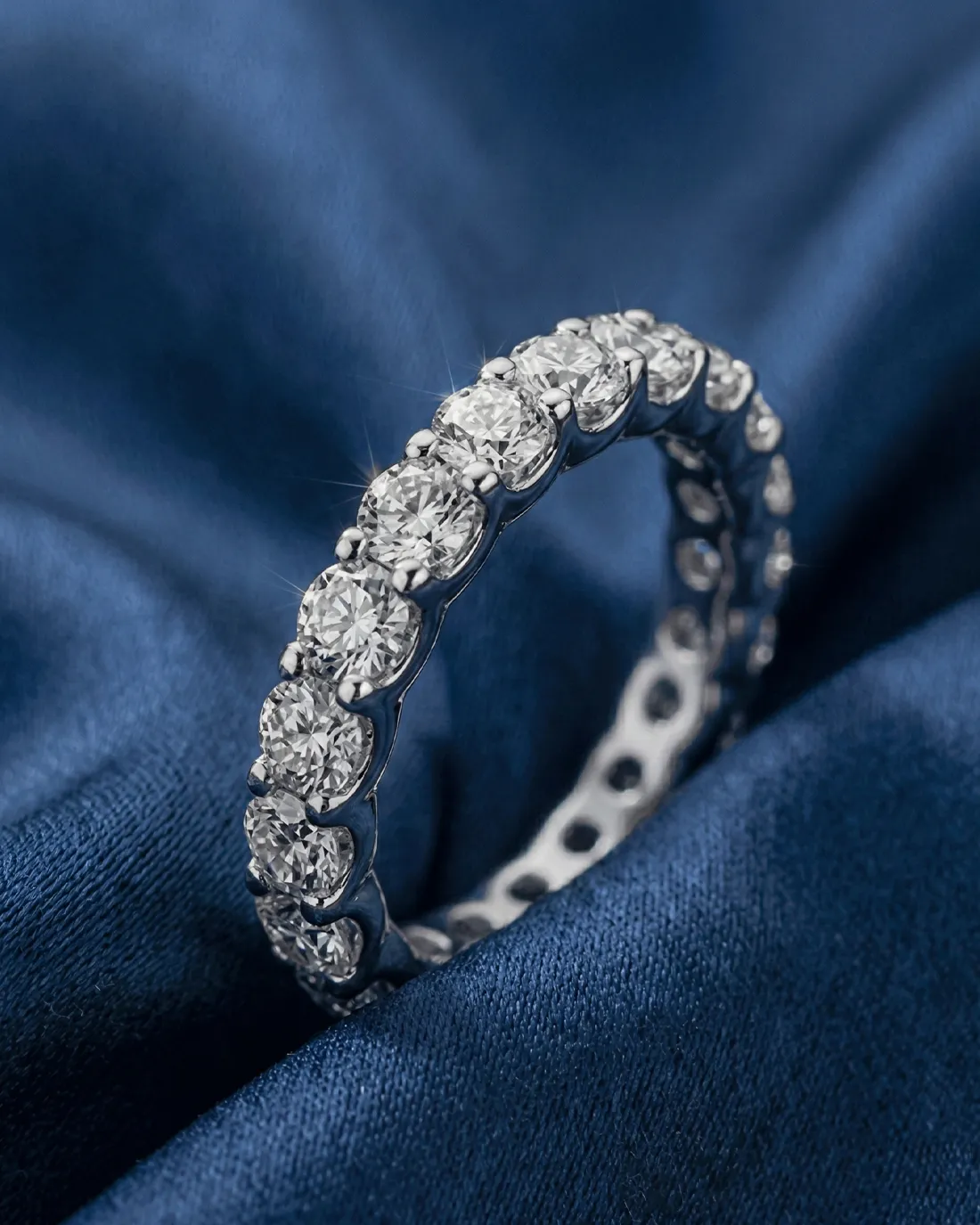Diamond eternity band on blue fabric background.