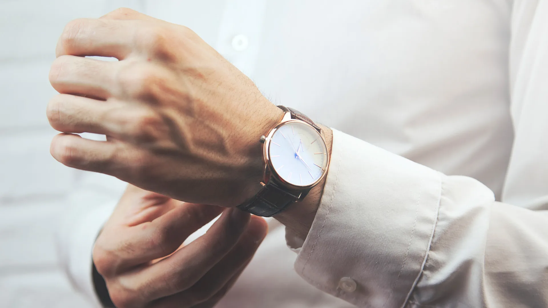 A man adjusts a stylish watch on his wrist, showcasing elegance and sophistication. Visit Quest Fine Jewelers in Fairfax.