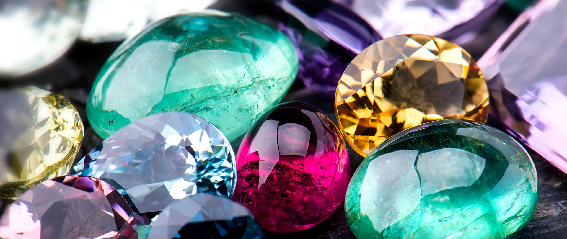 Vibrant assortment of loose gemstones including emeralds, rubies, and sapphires.