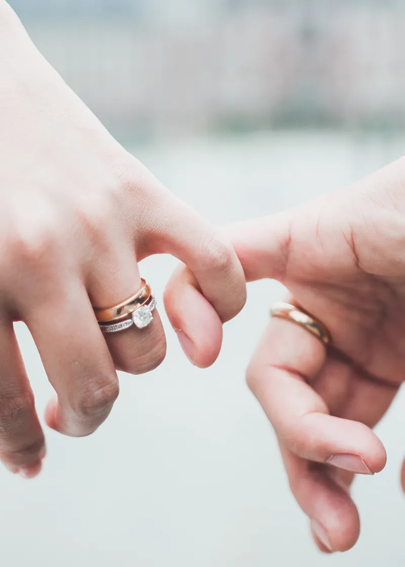 Engaged couple holding hands, showcasing an elegant engagement ring at Bryan Jewelry in Prattville.