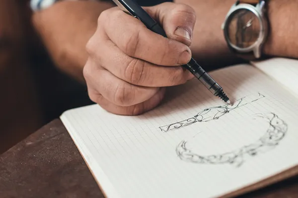 A jeweler sketching a design at the bench