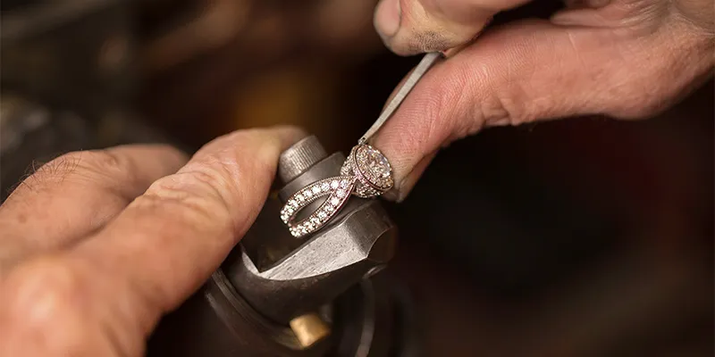 Jeweler polishing a diamond engagement ring at Quest Fine Jewelers in Fairfax.