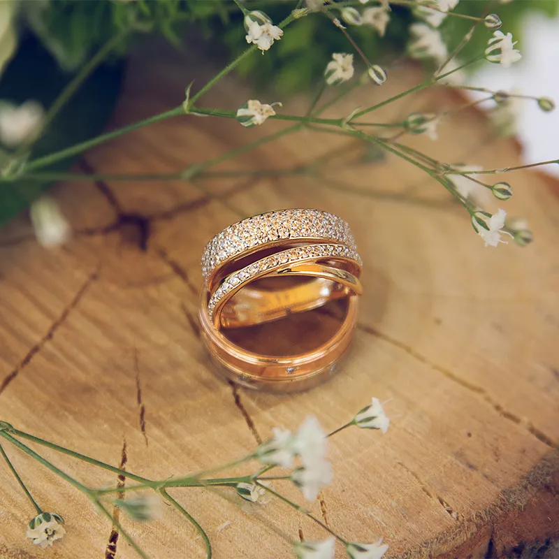 Three elegant gold rings on a pink background, showcasing different styles and designs. Click to explore more at Barthau Jewelle