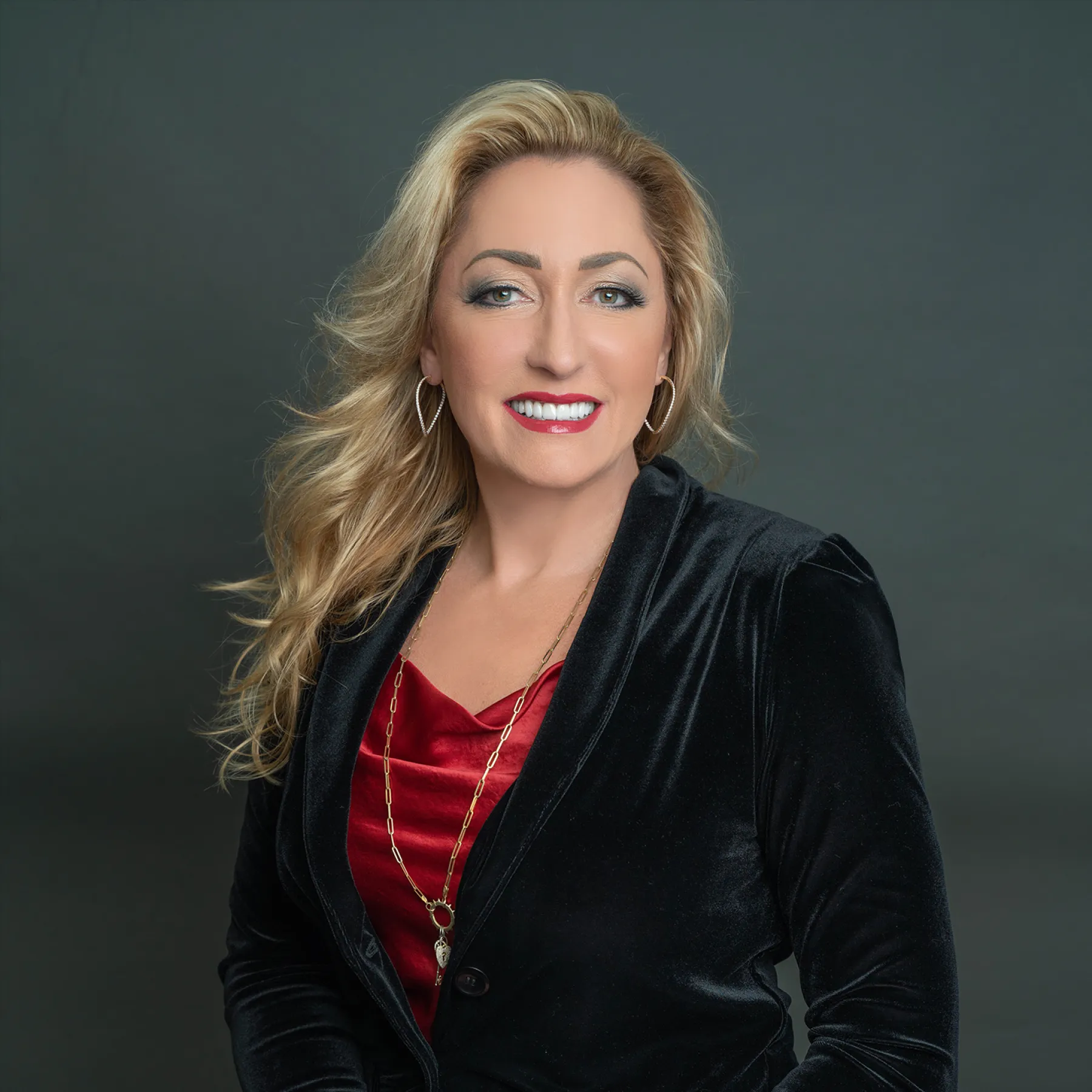Portrait of Pamela, wearing a black jacket and red top, representing P.J. Rossi Jewelers.